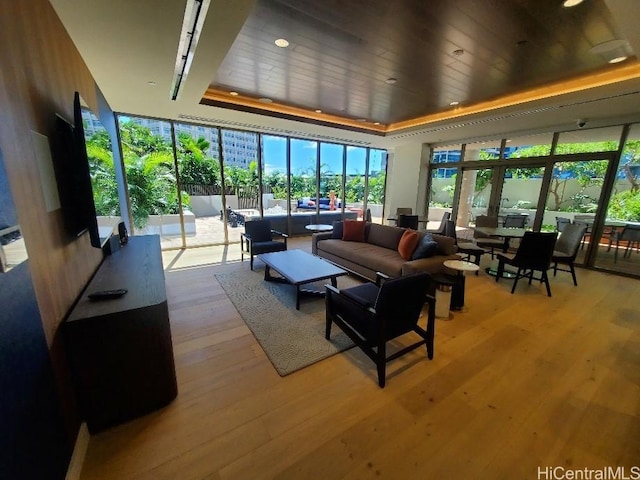 living room with a raised ceiling, light hardwood / wood-style flooring, and wooden ceiling