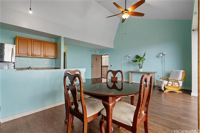 dining area with ceiling fan, dark hardwood / wood-style flooring, and high vaulted ceiling