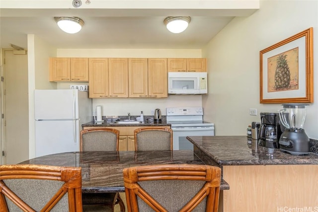 kitchen featuring white appliances, a kitchen breakfast bar, kitchen peninsula, and light brown cabinetry