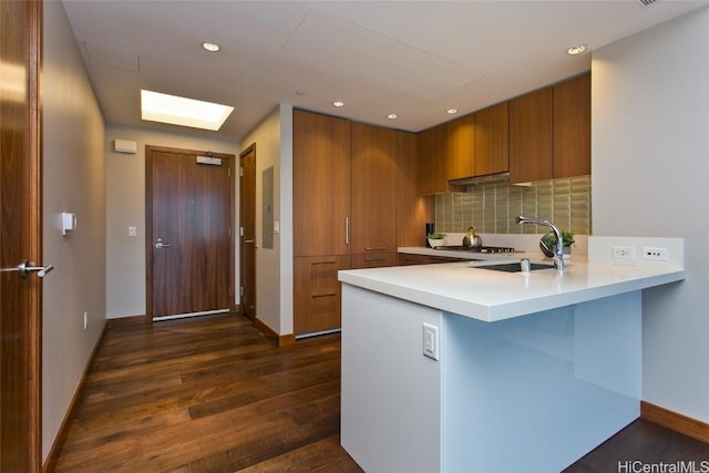 kitchen with sink, a breakfast bar, tasteful backsplash, dark hardwood / wood-style flooring, and kitchen peninsula