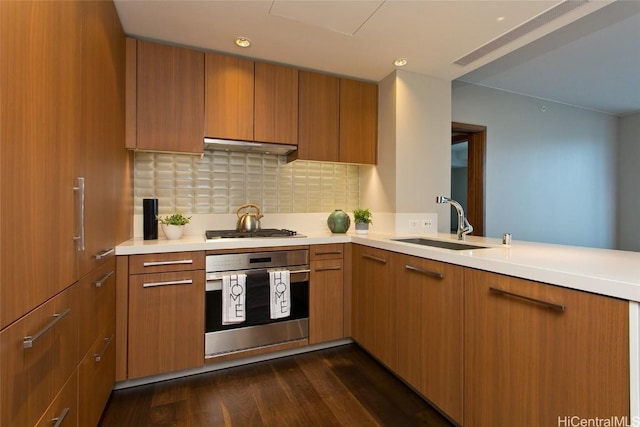 kitchen featuring sink, backsplash, dark hardwood / wood-style flooring, kitchen peninsula, and stainless steel appliances