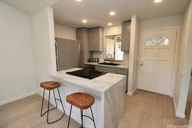 kitchen featuring sink, gray cabinets, decorative backsplash, and stainless steel fridge