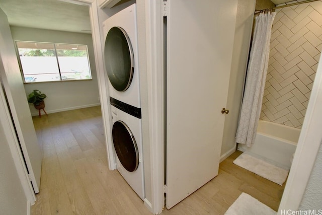 clothes washing area featuring stacked washer and clothes dryer and light wood-type flooring