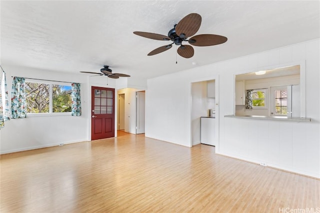 unfurnished living room featuring a textured ceiling, light hardwood / wood-style flooring, and a healthy amount of sunlight