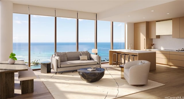 living room with floor to ceiling windows, a water view, sink, and light hardwood / wood-style flooring