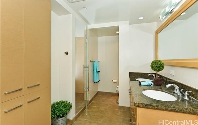 bathroom with vanity, a shower with shower door, tile patterned floors, and toilet