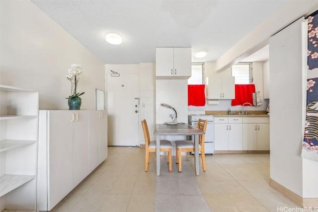 kitchen with white range, a sink, white cabinetry, light countertops, and open shelves