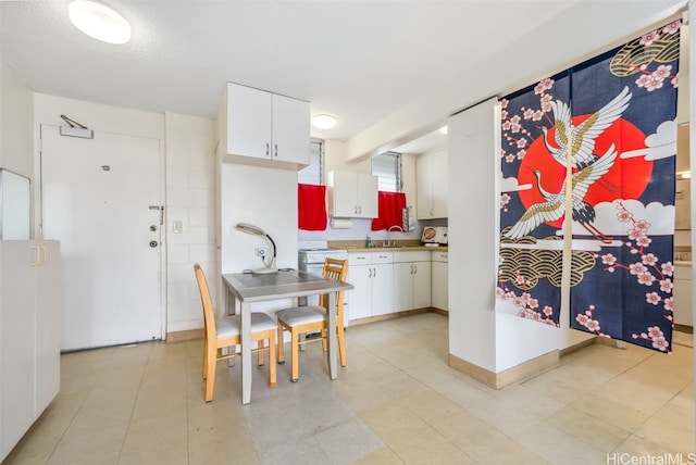 kitchen with light countertops, white cabinets, range with electric stovetop, and a sink