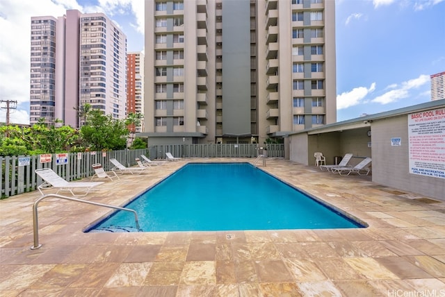 community pool with a view of city, fence, and a patio