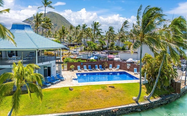 view of pool with a patio, a mountain view, and a yard