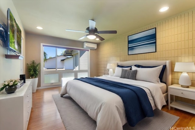 bedroom featuring hardwood / wood-style floors, an AC wall unit, and ceiling fan