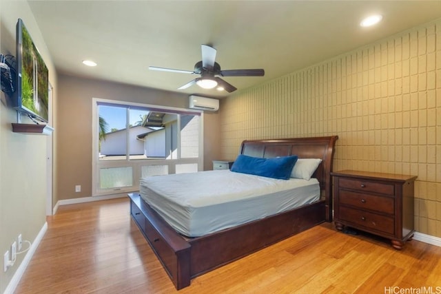 bedroom with an AC wall unit, ceiling fan, and light hardwood / wood-style flooring