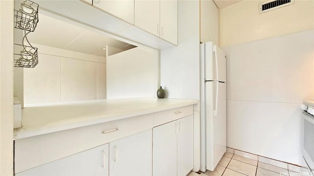 kitchen with white cabinetry, light tile patterned floors, white refrigerator, and stove