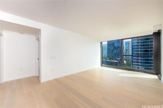 unfurnished room with a wall of windows and light wood-type flooring