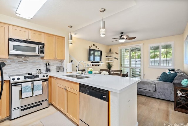 kitchen with appliances with stainless steel finishes, light brown cabinetry, kitchen peninsula, and sink