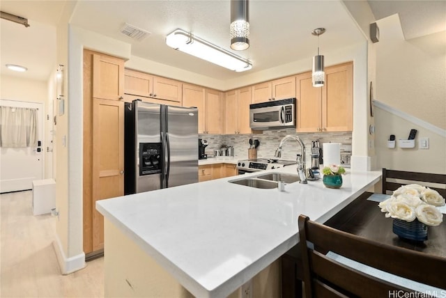 kitchen with pendant lighting, sink, appliances with stainless steel finishes, backsplash, and light brown cabinetry