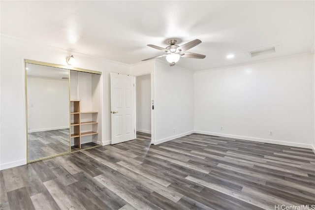 unfurnished bedroom featuring dark wood-type flooring, ornamental molding, a closet, and ceiling fan