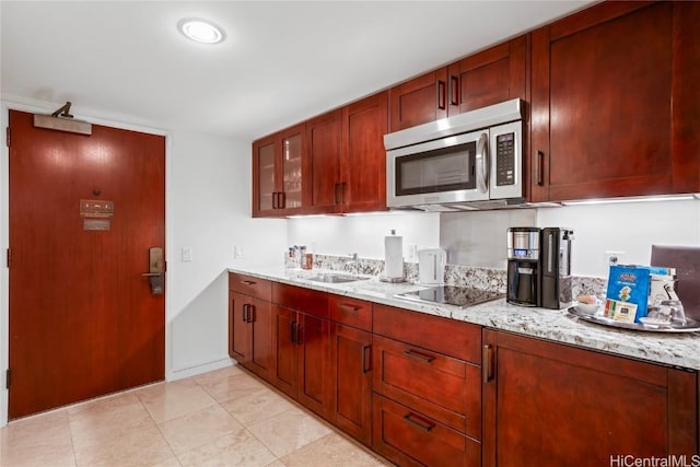 kitchen with sink, black electric stovetop, and light stone counters