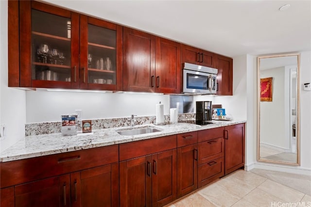 kitchen featuring light stone countertops, sink, light tile patterned floors, and black electric cooktop