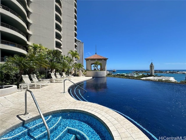 view of pool with a community hot tub, a water view, and a patio