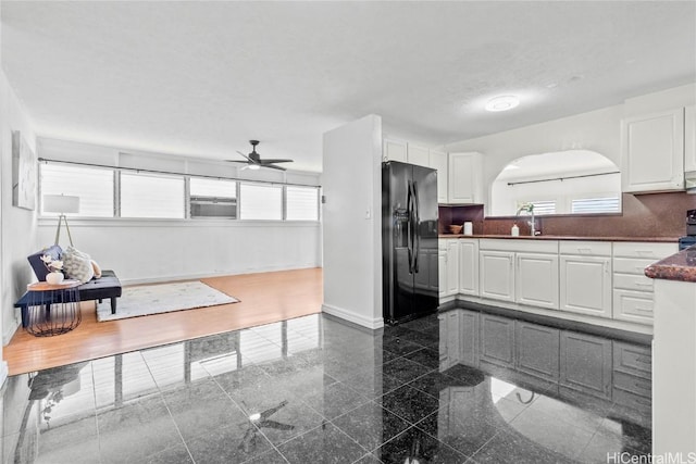 kitchen featuring backsplash, a wealth of natural light, black refrigerator with ice dispenser, and white cabinets