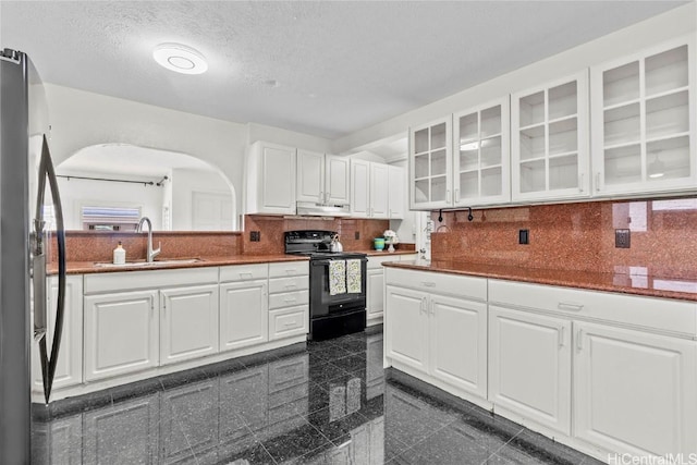 kitchen featuring black electric range oven, sink, white cabinetry, fridge, and tasteful backsplash