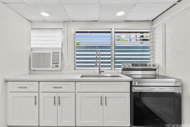 kitchen with white cabinetry, a drop ceiling, and electric range