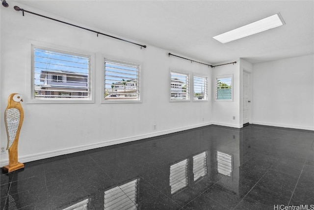 unfurnished room featuring a skylight