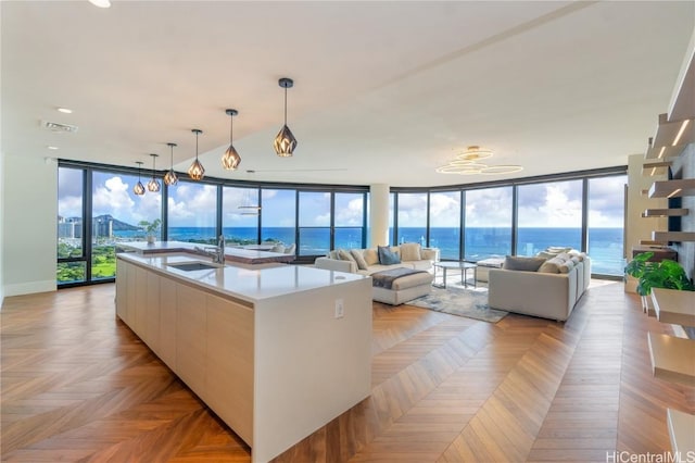 living room with expansive windows, a water view, sink, and a wealth of natural light