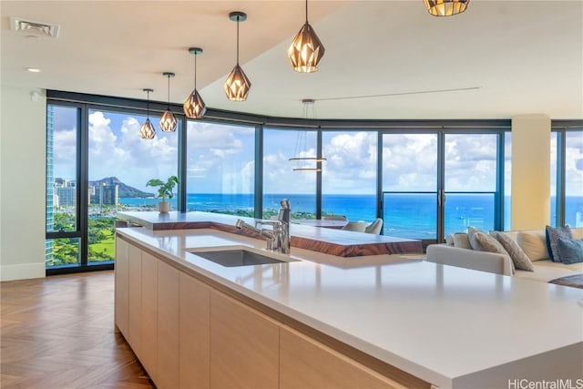 kitchen featuring hanging light fixtures, a water view, sink, and parquet flooring