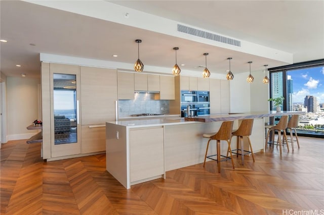 kitchen with pendant lighting, a spacious island, stainless steel gas cooktop, decorative backsplash, and light parquet flooring