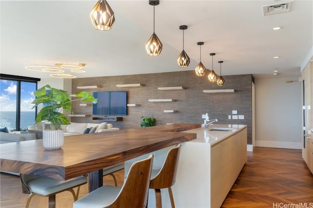 kitchen with a water view, dark parquet flooring, decorative light fixtures, and sink