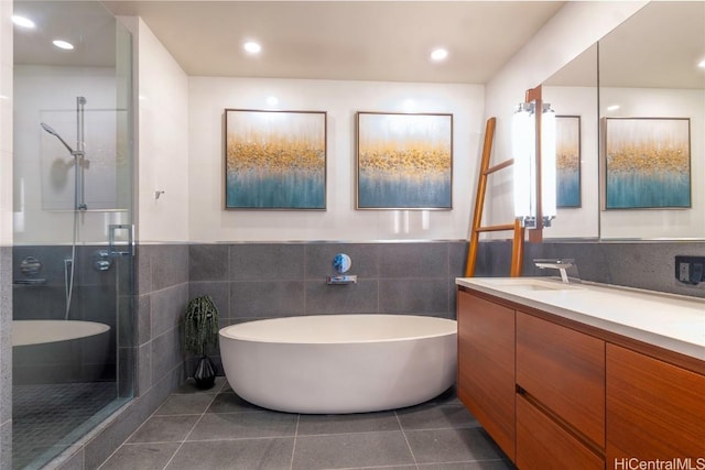 bathroom featuring tile patterned flooring, vanity, independent shower and bath, and tile walls