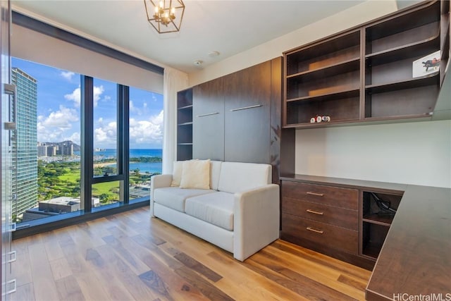 interior space featuring a wall of windows, light hardwood / wood-style floors, a chandelier, and a water view