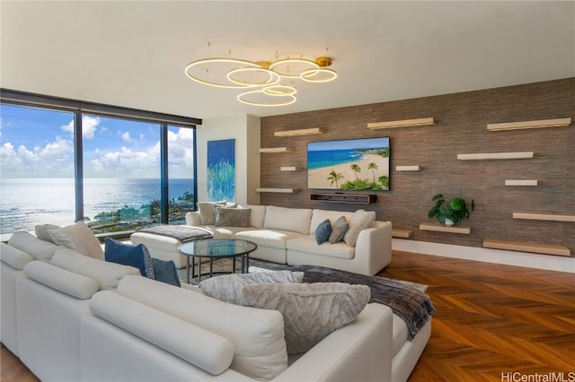 living room with wood walls, dark parquet floors, floor to ceiling windows, and a water view