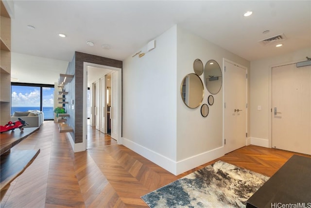 corridor featuring parquet floors, a water view, and expansive windows