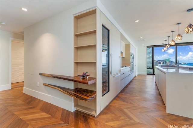 corridor featuring built in shelves, floor to ceiling windows, sink, a chandelier, and light parquet floors