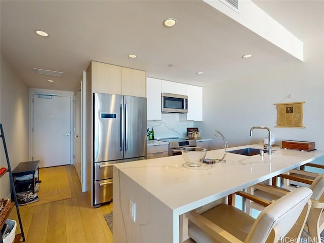 kitchen with a kitchen island with sink, sink, light hardwood / wood-style flooring, and stainless steel appliances