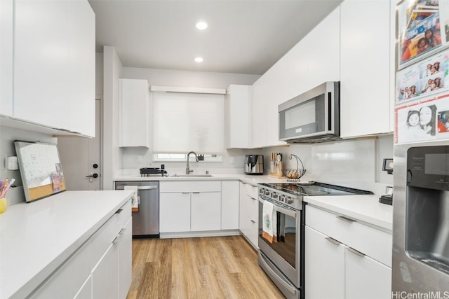 kitchen featuring white cabinetry, sink, stainless steel appliances, and light wood-type flooring