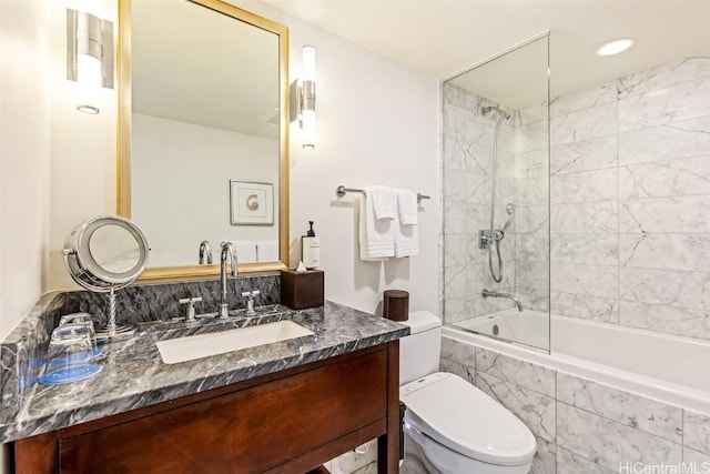 full bathroom featuring tiled shower / bath, vanity, and toilet