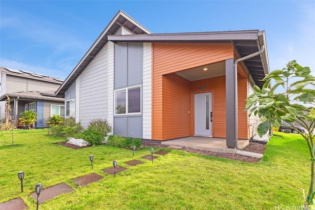 back of property featuring a patio area and a lawn