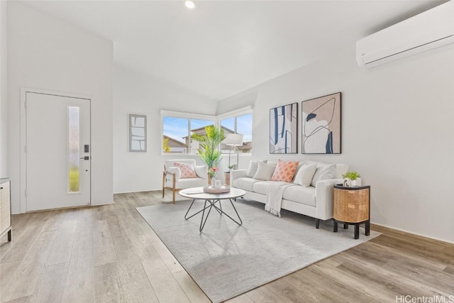 living room with vaulted ceiling, a wall mounted AC, and light hardwood / wood-style flooring