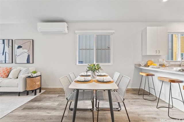 dining space with light wood-type flooring and an AC wall unit