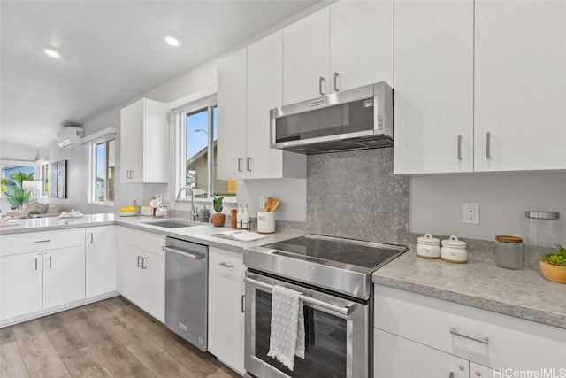 kitchen featuring white cabinetry, stainless steel appliances, a wall mounted AC, and sink