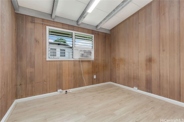 spare room featuring light hardwood / wood-style flooring, beam ceiling, and wood walls