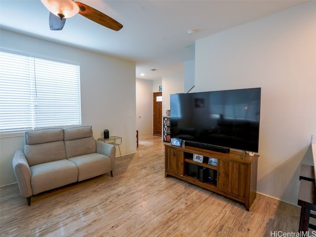 living room with a wealth of natural light, light hardwood / wood-style flooring, and ceiling fan