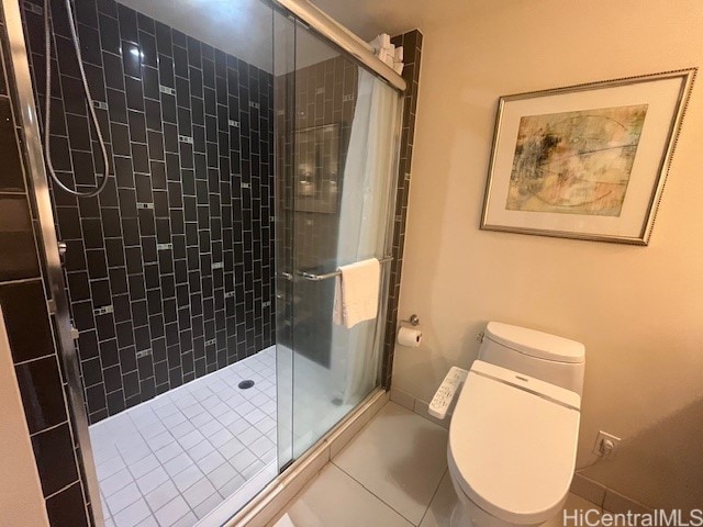 bathroom featuring toilet, a shower with shower door, and tile patterned flooring