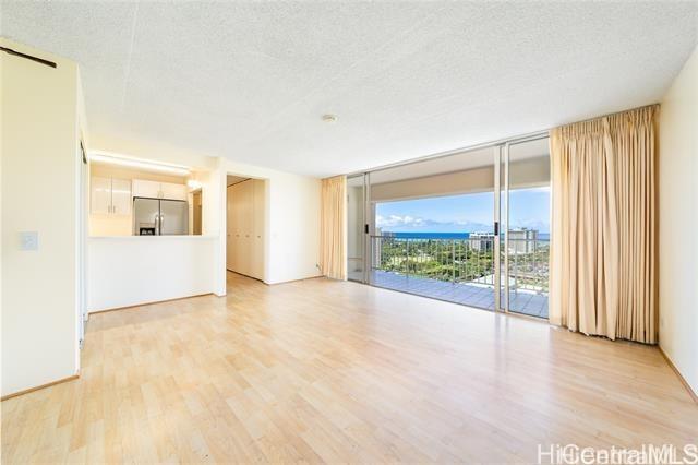 unfurnished living room with expansive windows, a textured ceiling, and light wood-type flooring