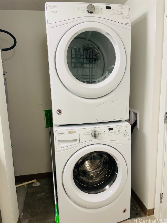 laundry area with stacked washer / drying machine, baseboards, and laundry area