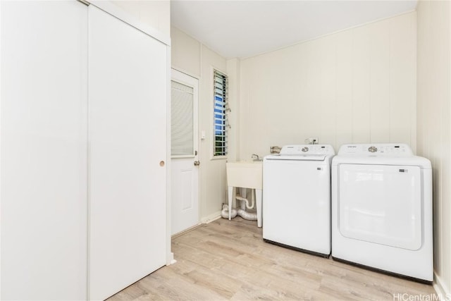 laundry area with light hardwood / wood-style floors and washing machine and dryer